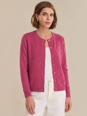 Woman wearing a pink cardigan over a white top on a beige background