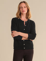 Woman wearing a black ribbed sweater with button details on a beige background