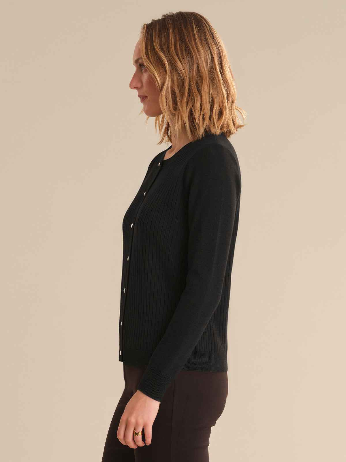 Woman wearing a black cardigan against a beige background
