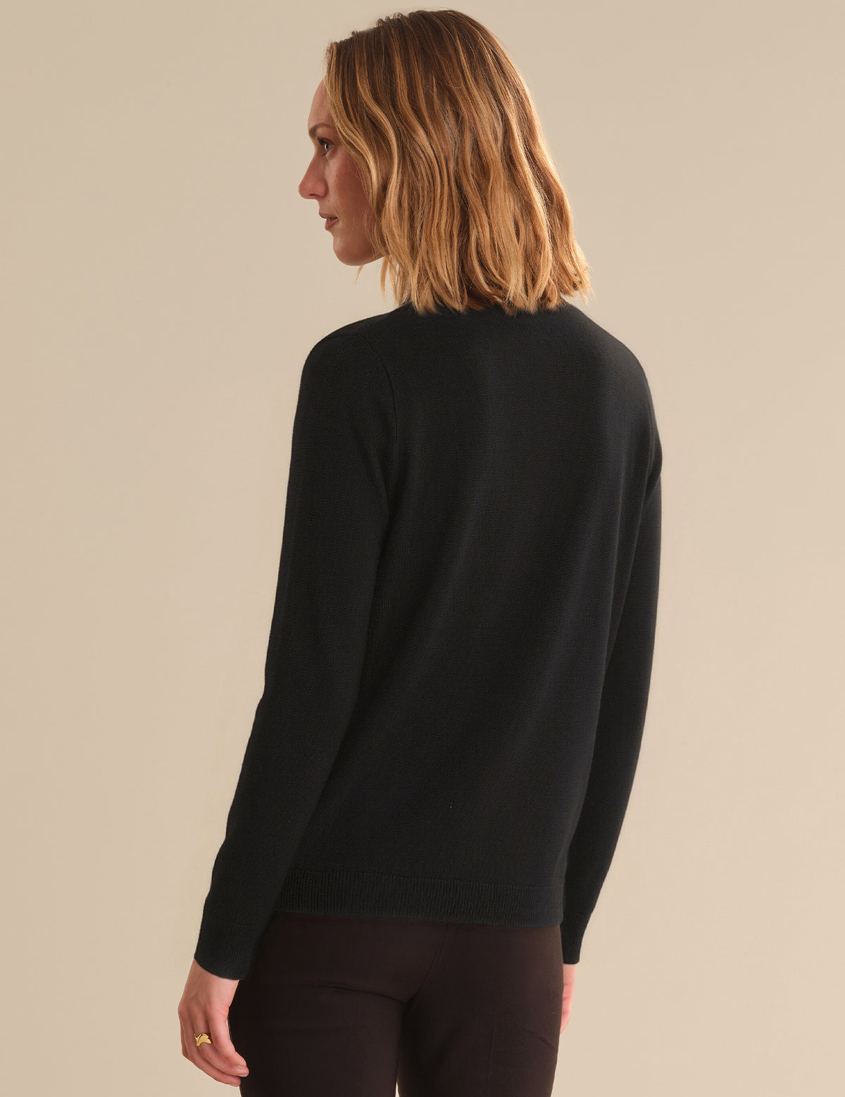 Person wearing a black sweater against a beige background