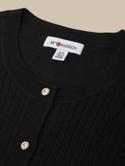 Black ribbed sweater with decorative buttons and a visible brand label on a beige background