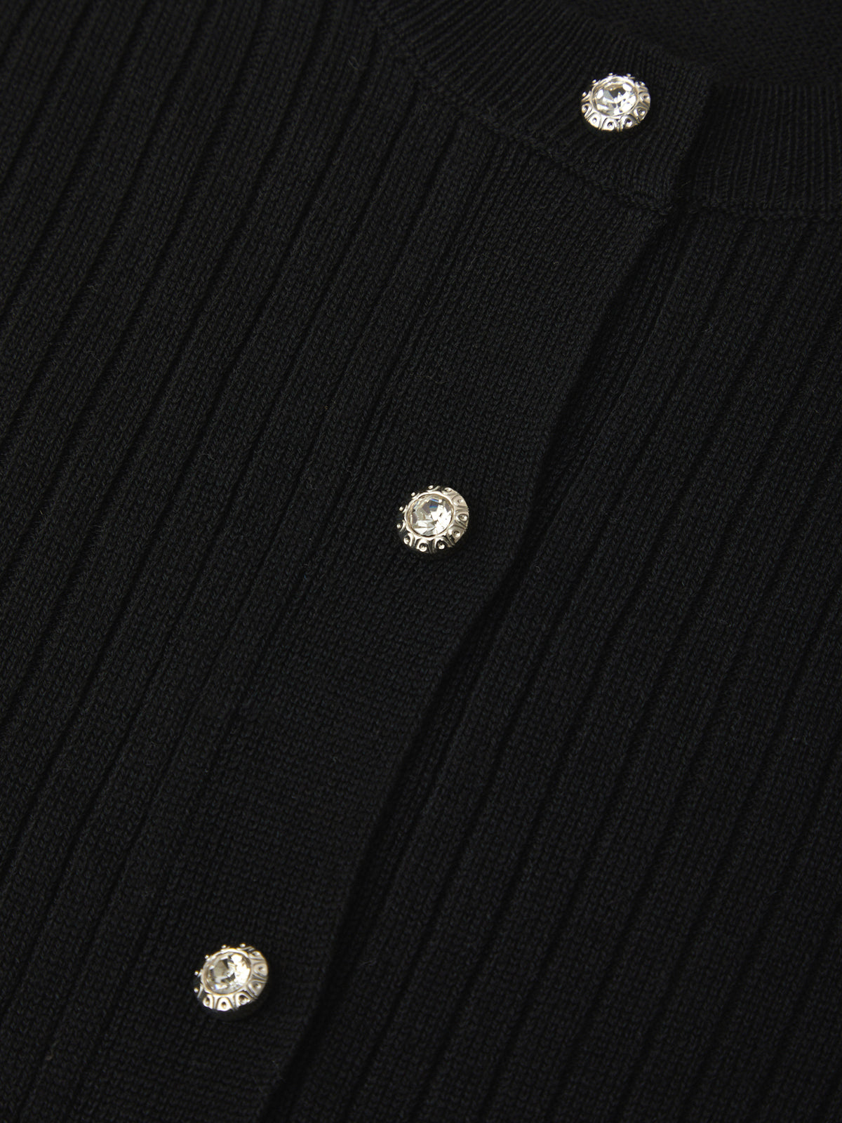 Close-up of a black ribbed sweater with crystal buttons on a dark background