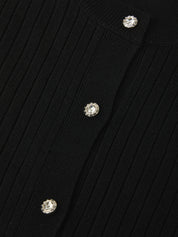 Close-up of a black ribbed sweater with crystal buttons on a dark background
