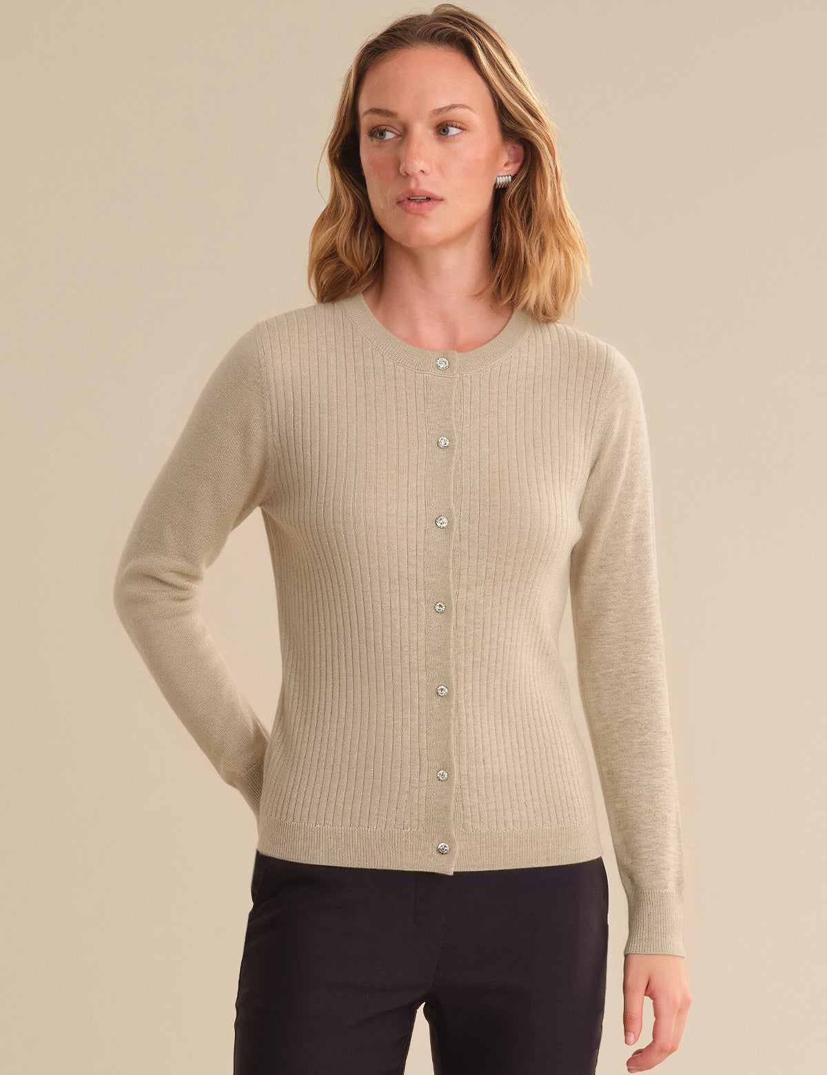 Woman wearing a beige cardigan against a plain background