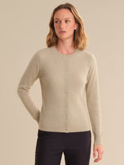 Woman wearing a beige cardigan against a plain background