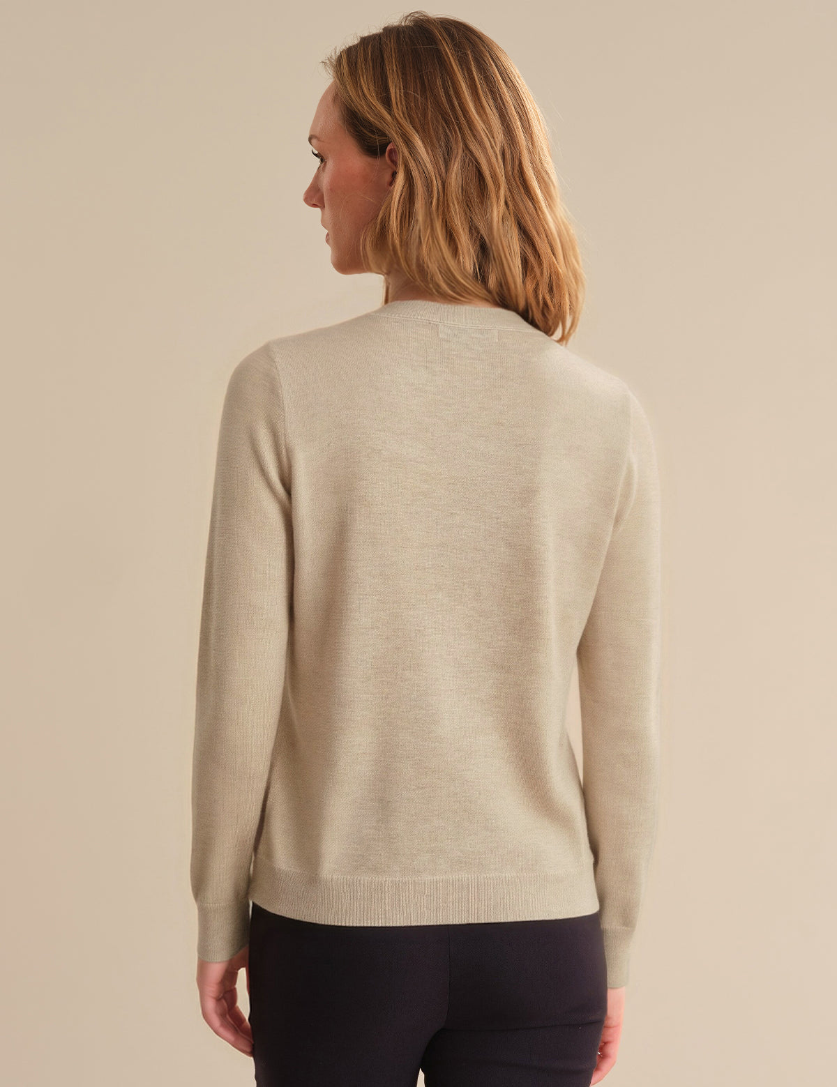 Woman wearing a beige sweater against a beige background