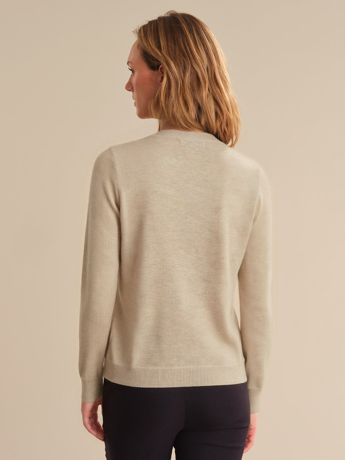 Woman wearing a beige sweater against a beige background