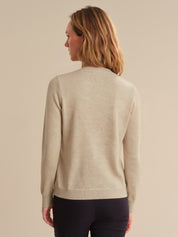Woman wearing a beige sweater against a beige background