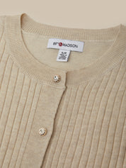 Close-up of a beige ribbed sweater with a brand label on a beige background