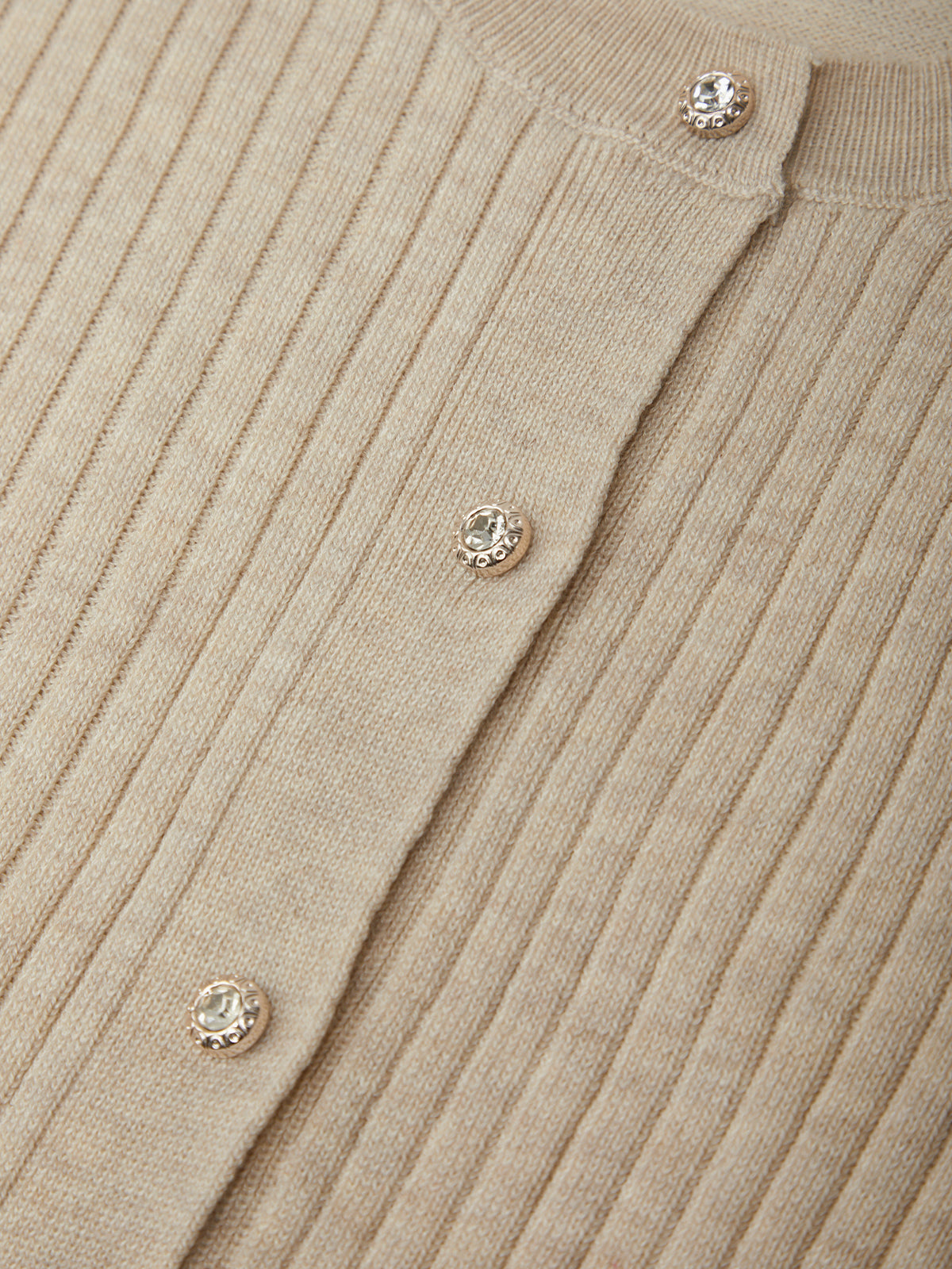 Close-up of a beige ribbed sweater with decorative buttons.