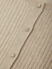 Close-up of a beige ribbed sweater with decorative buttons.