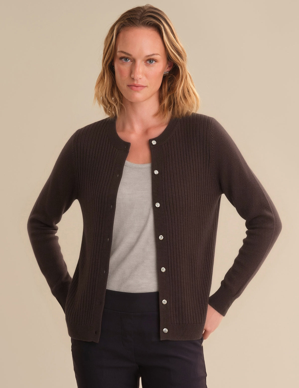 Woman wearing a brown cardigan over a gray shirt on a beige background