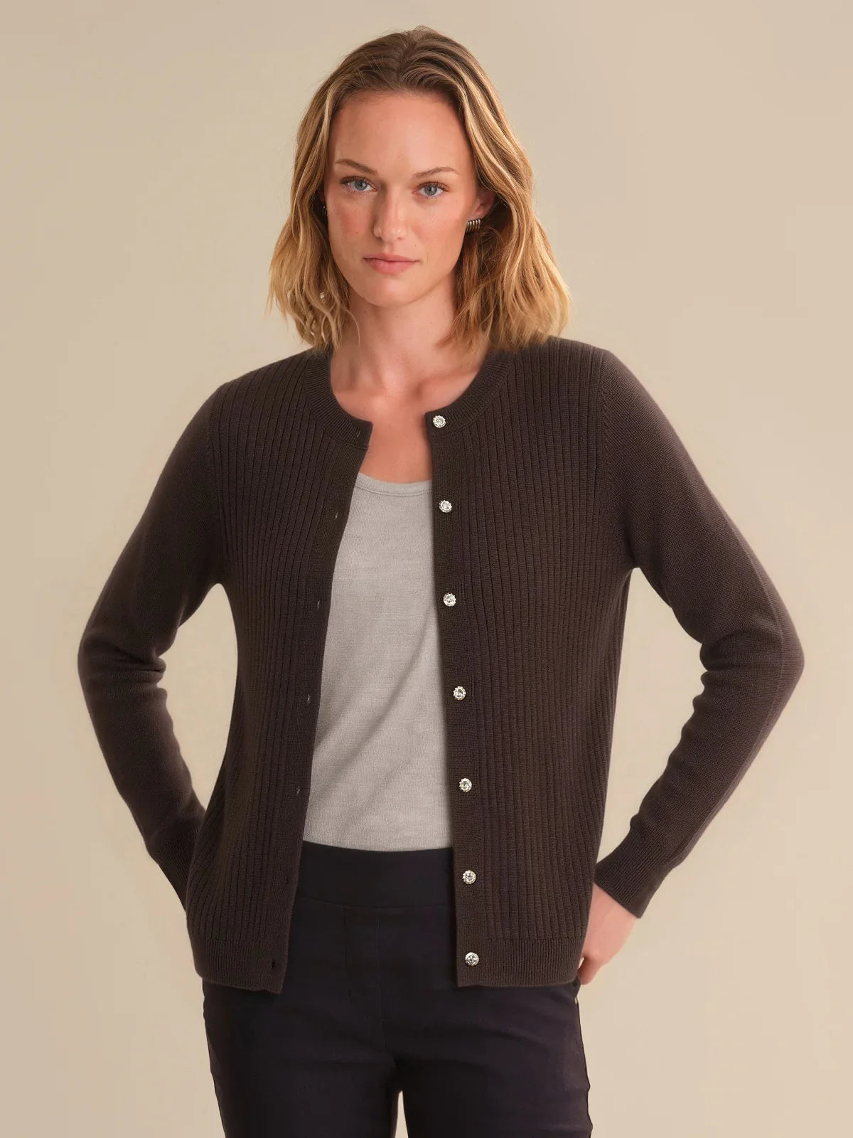 Woman wearing a brown cardigan over a gray shirt on a beige background
