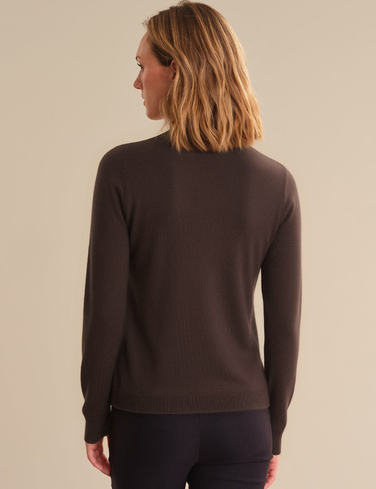 Person wearing a brown sweater on a beige background
