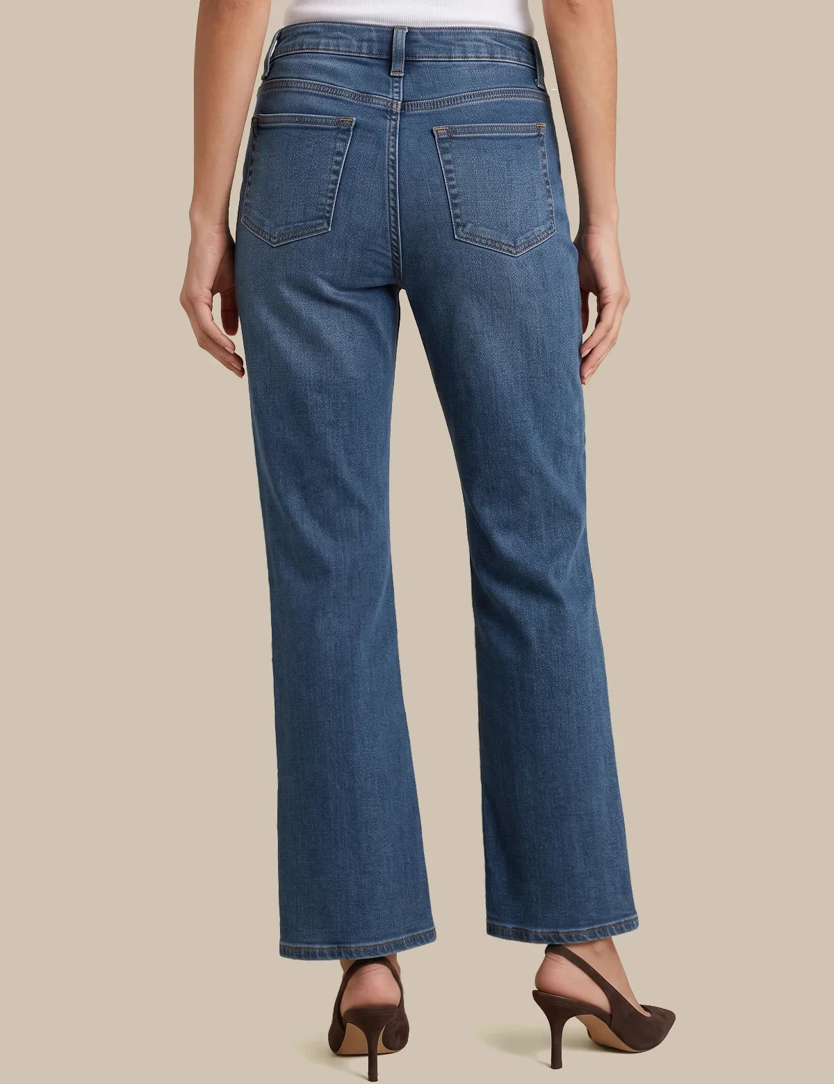 Rear view of a model wearing blue high-waisted straight-leg jeans with brown high-heeled sandals against a solid beige background.