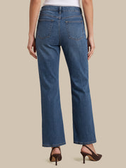 Rear view of a model wearing blue high-waisted straight-leg jeans with brown high-heeled sandals against a solid beige background.