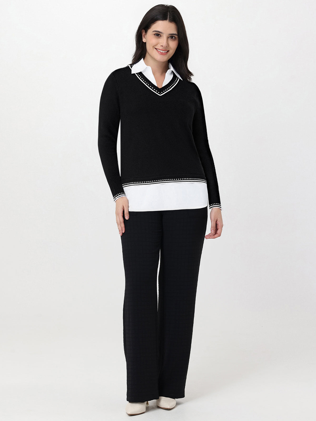 Woman wearing a black sweater with white trim and matching pants on a white background