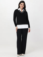 Woman wearing a black sweater with white trim and matching pants on a white background