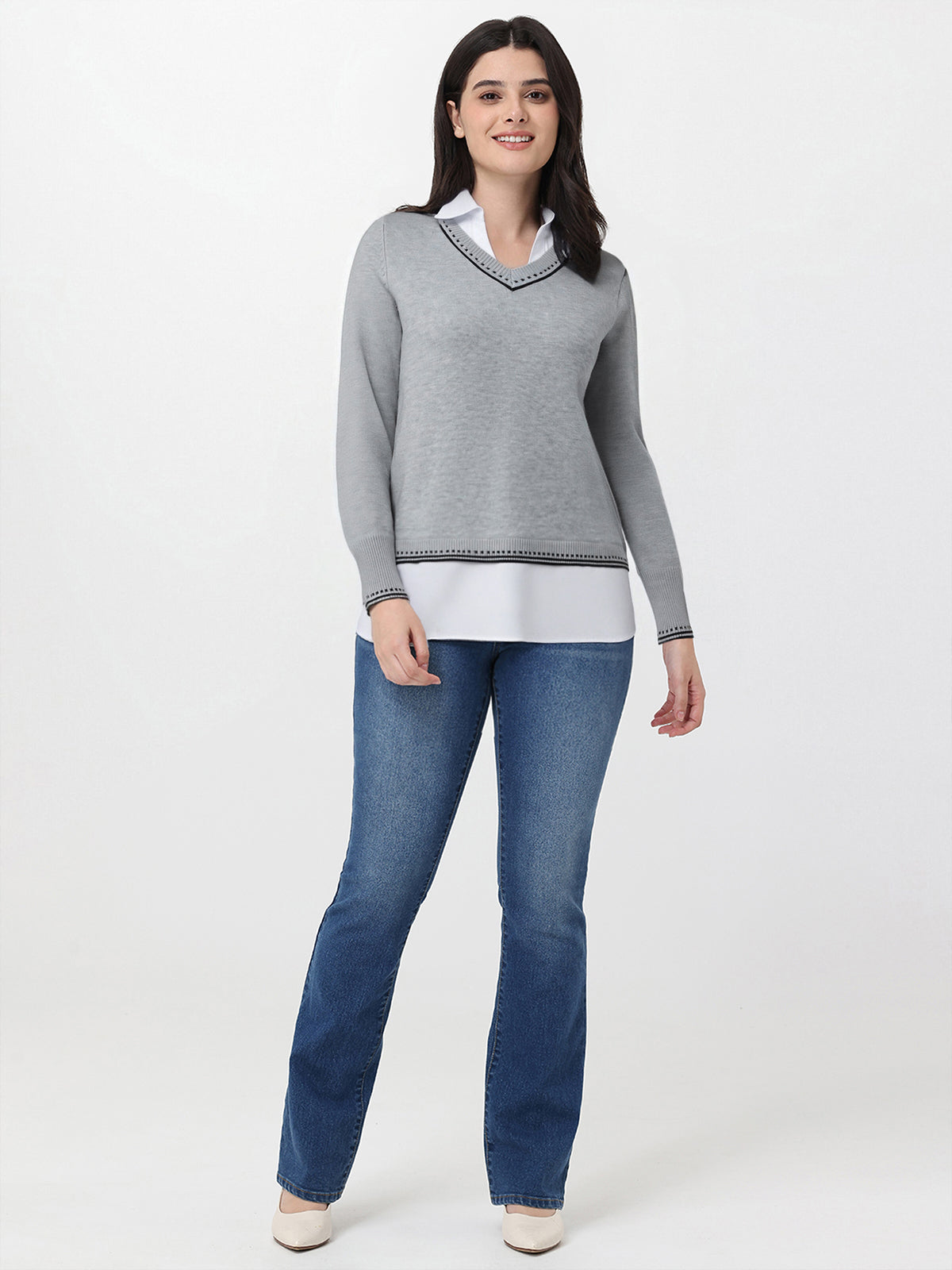 Woman wearing a gray sweater and blue jeans on a white background