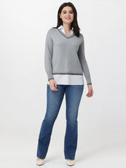 Woman wearing a gray sweater and blue jeans on a white background