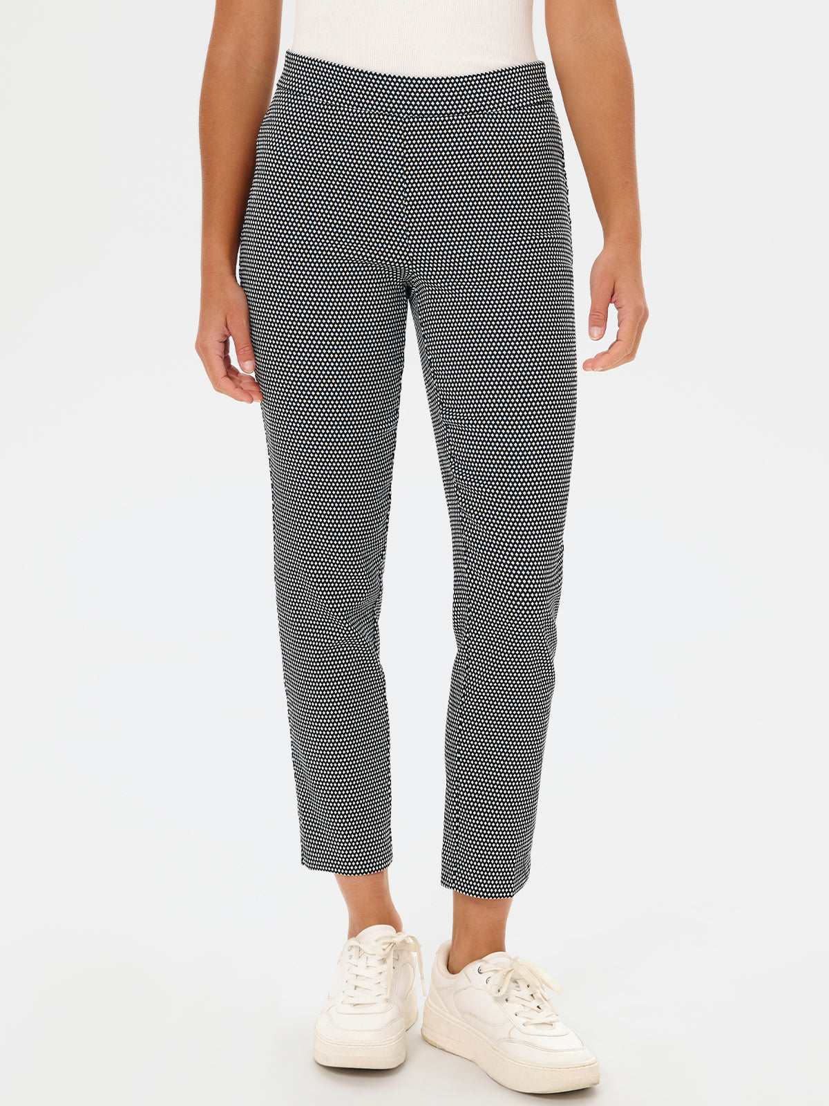 Person wearing black and white patterned pants on a white background