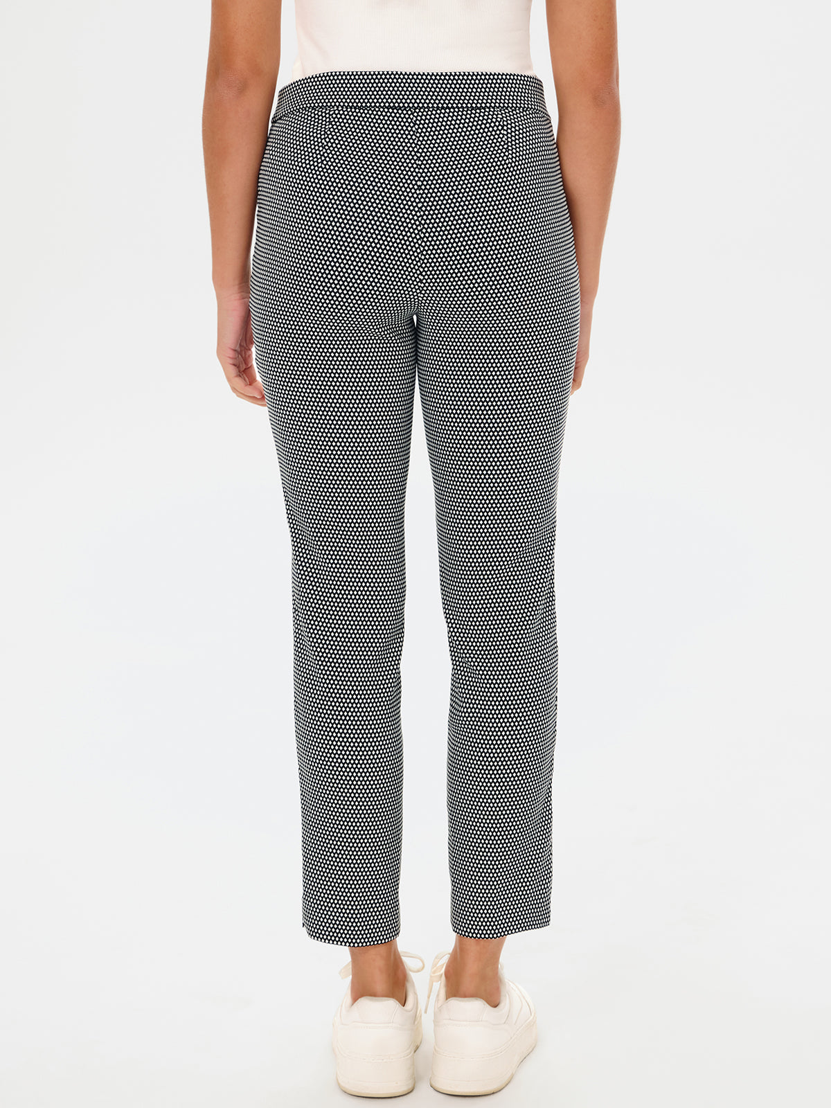 Person wearing black and white patterned pants on a white background