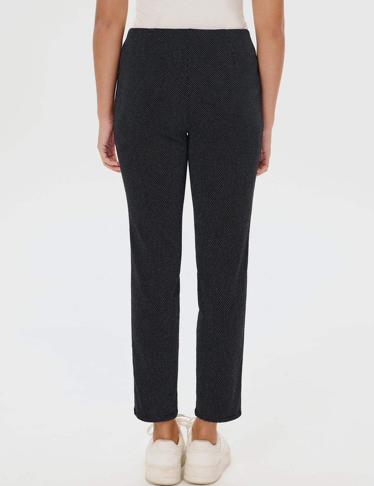 Black patterned pants worn by a person on a white background