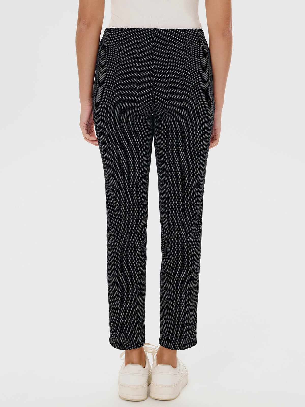 Black patterned pants worn by a person on a white background