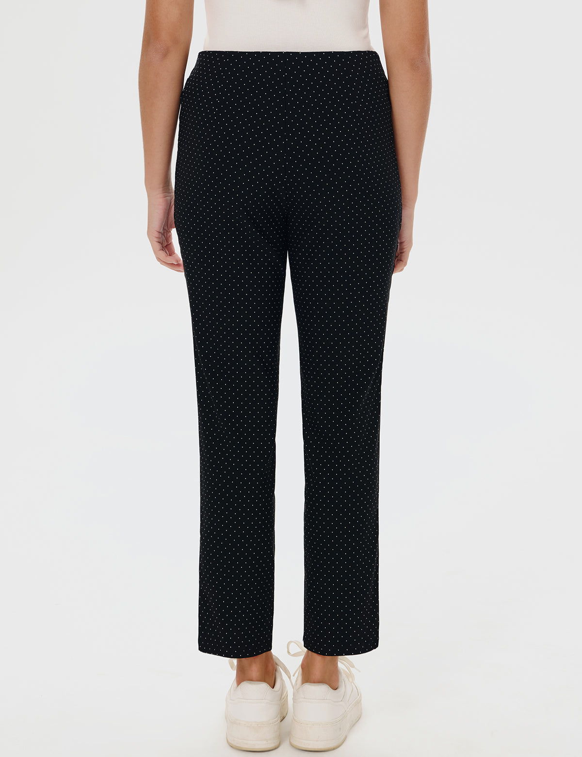 Black polka dot pants worn by a person on a white background