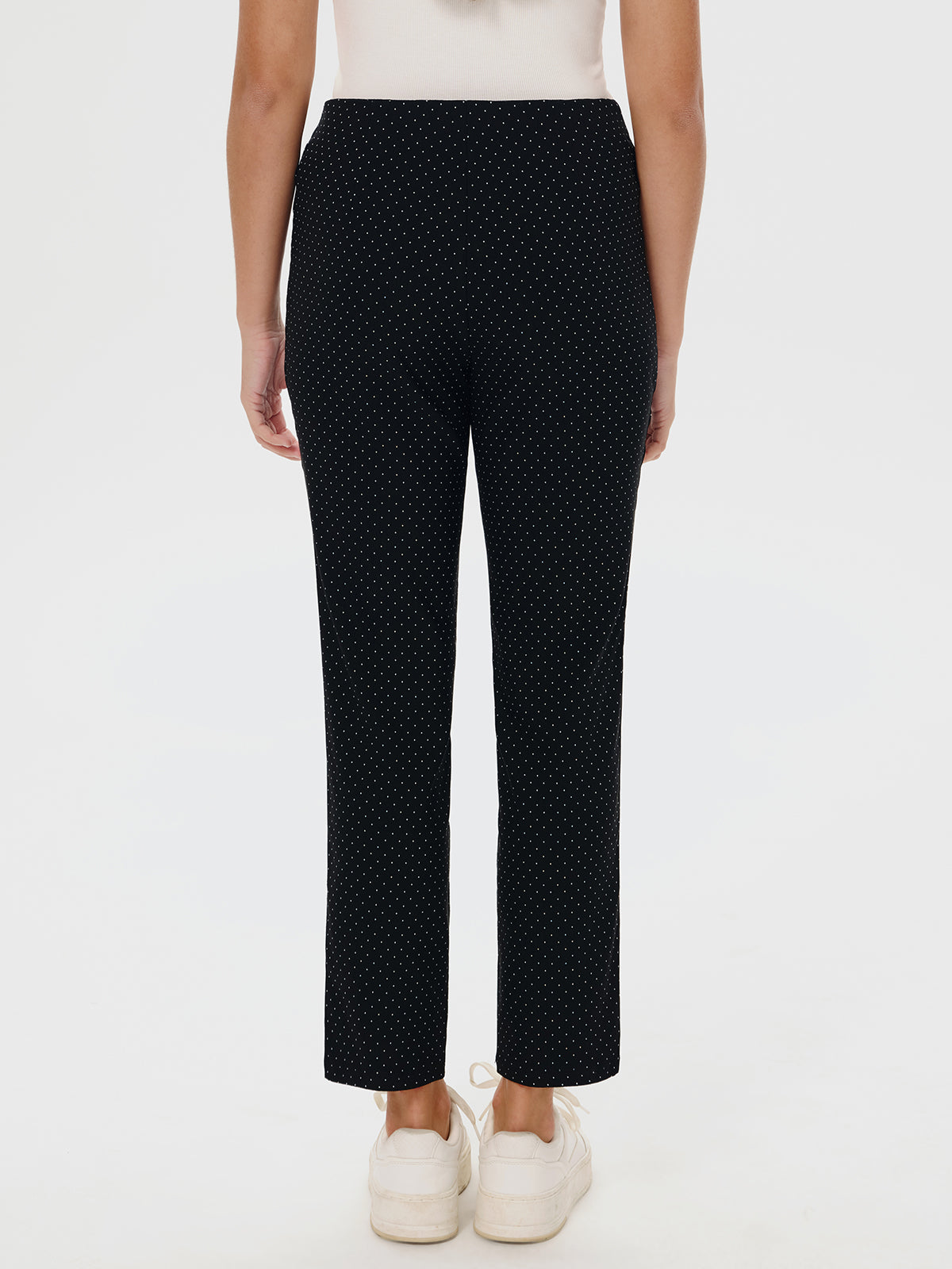 Black polka dot pants worn by a person on a white background