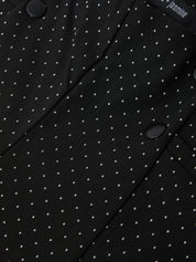 Close-up of a black fabric with white polka dots and a brand label.
