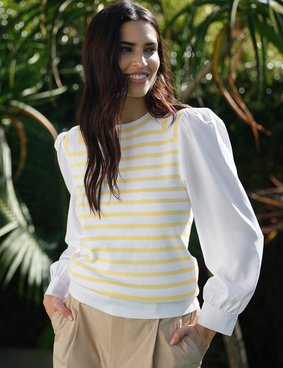 Woman wearing a white and yellow striped sweater with puffed sleeves outdoors.