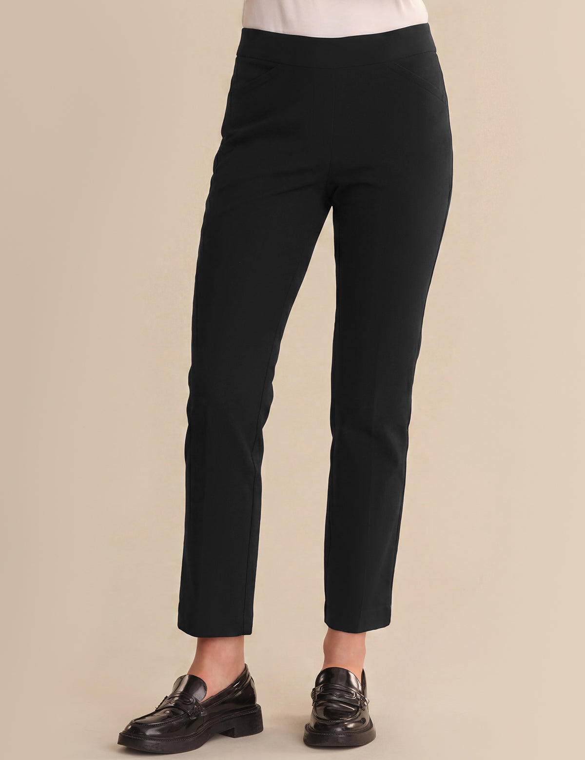 Black pants worn by a person on a beige background