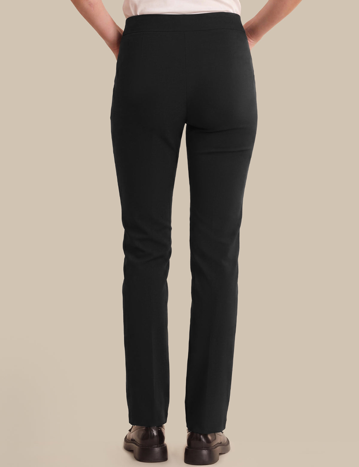 Person wearing black pants on a beige background