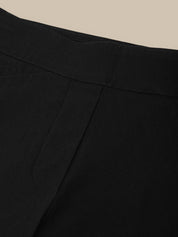 Close-up of black pants with a beige background