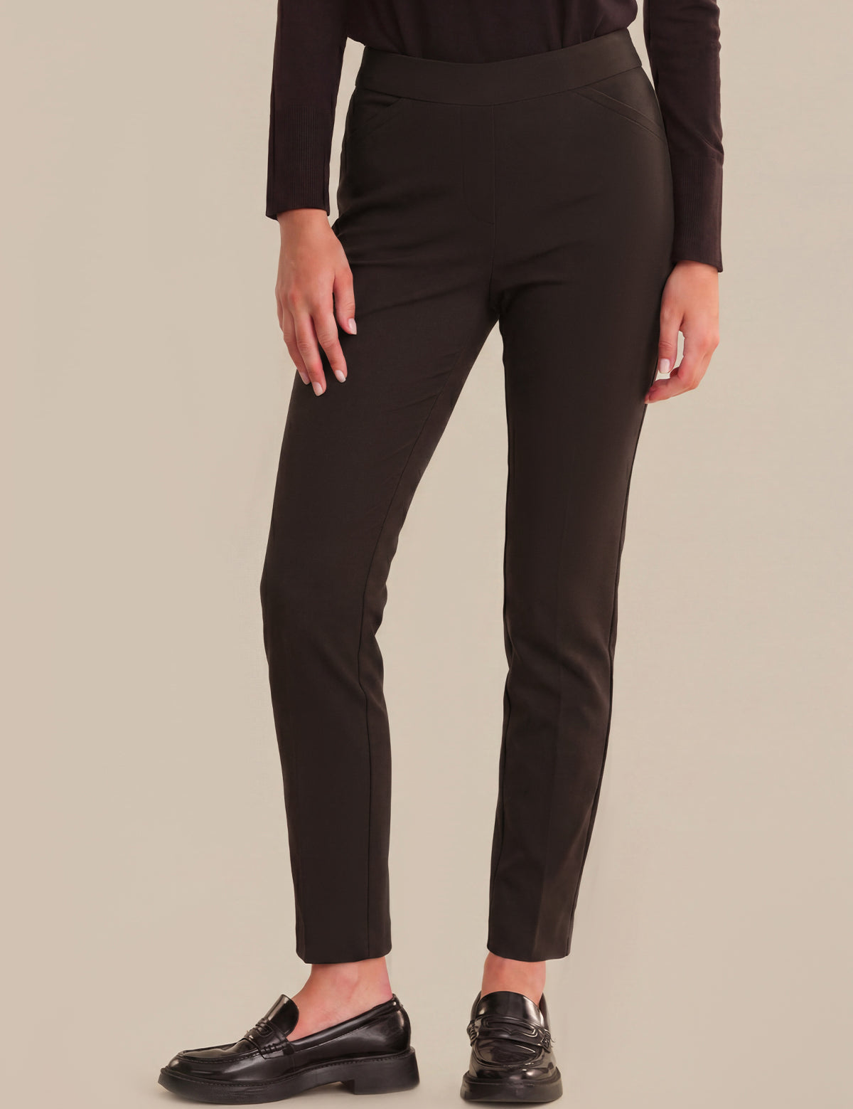 Person wearing black pants on a beige background