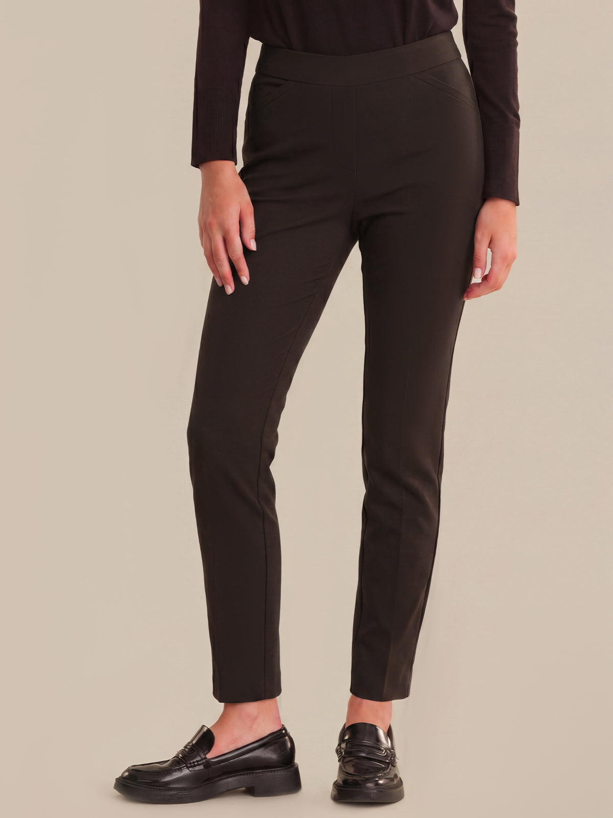 Person wearing black pants on a beige background