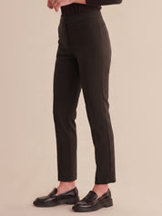 Person wearing black pants and black shoes on a beige background