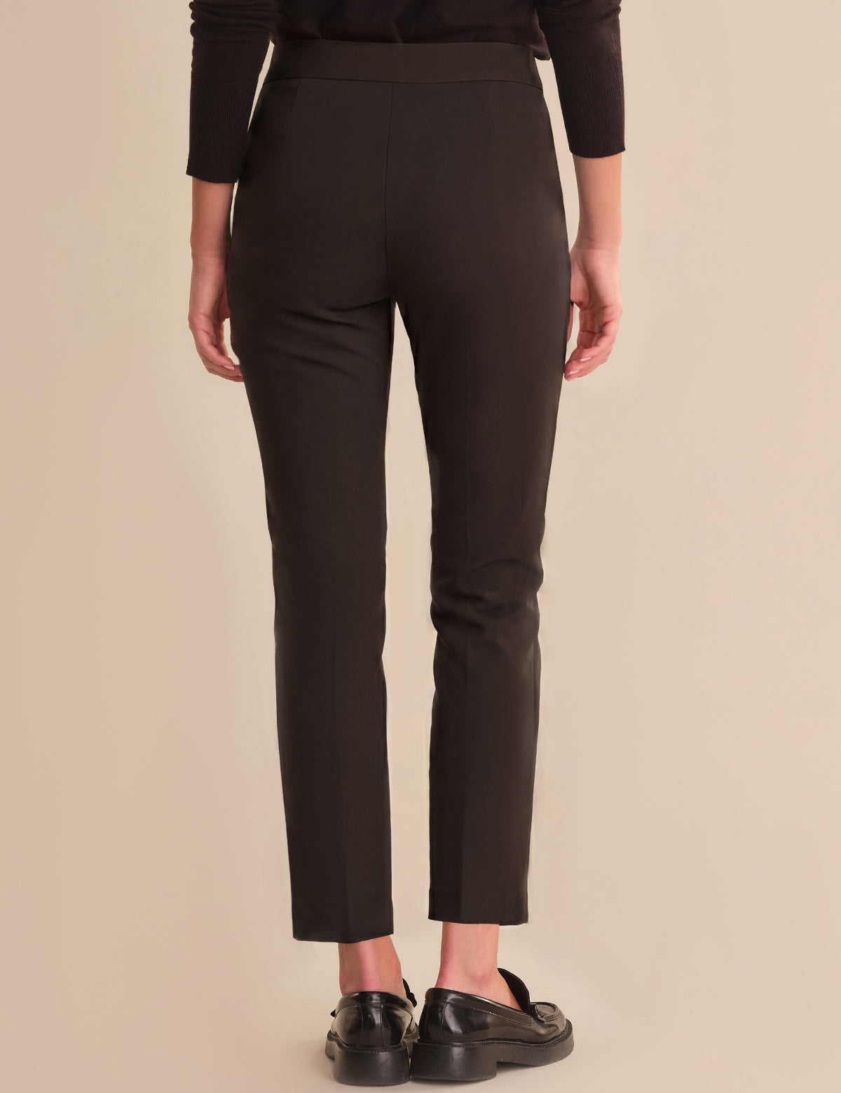 Person wearing black pants on a beige background