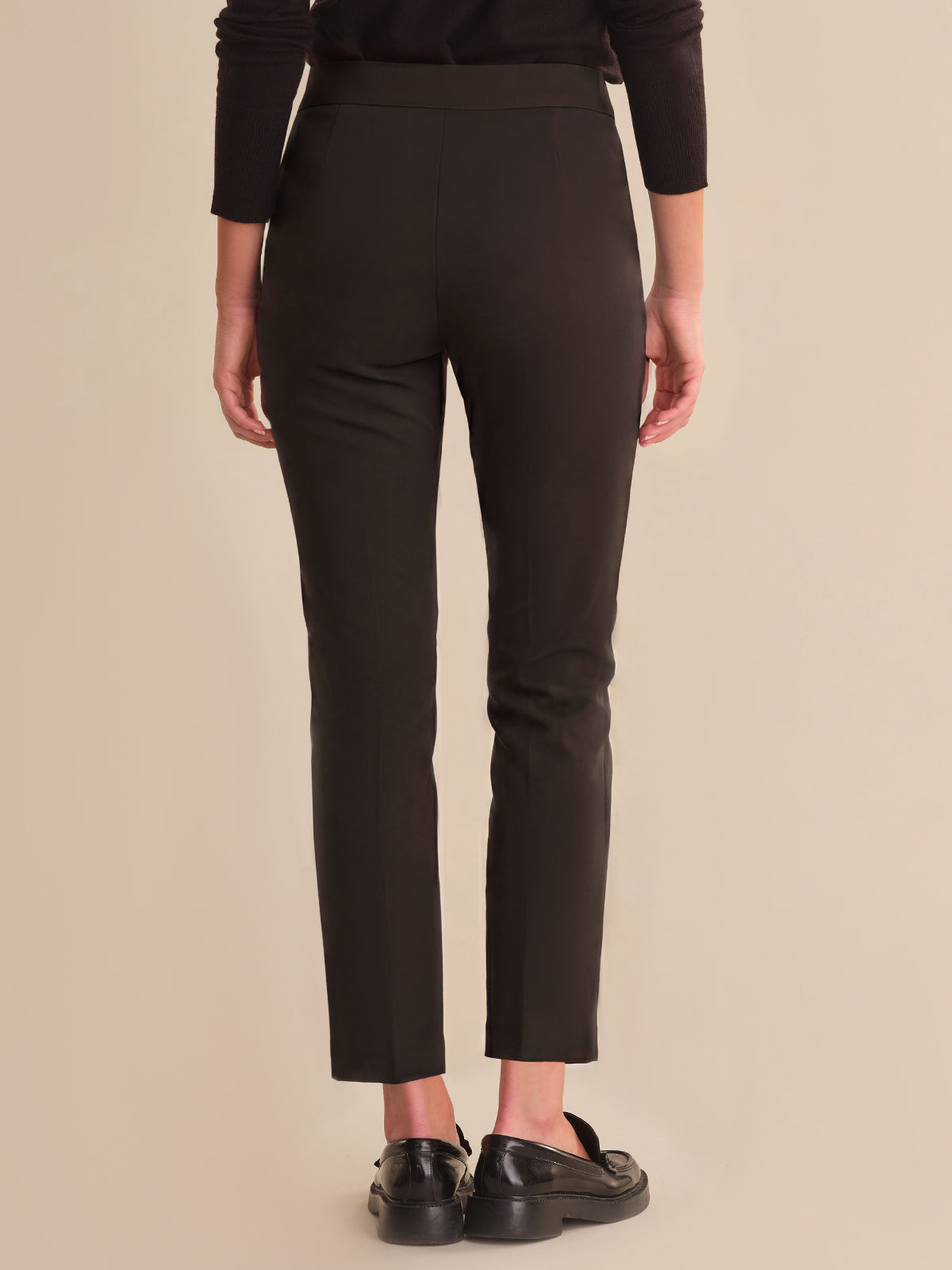Person wearing black pants on a beige background