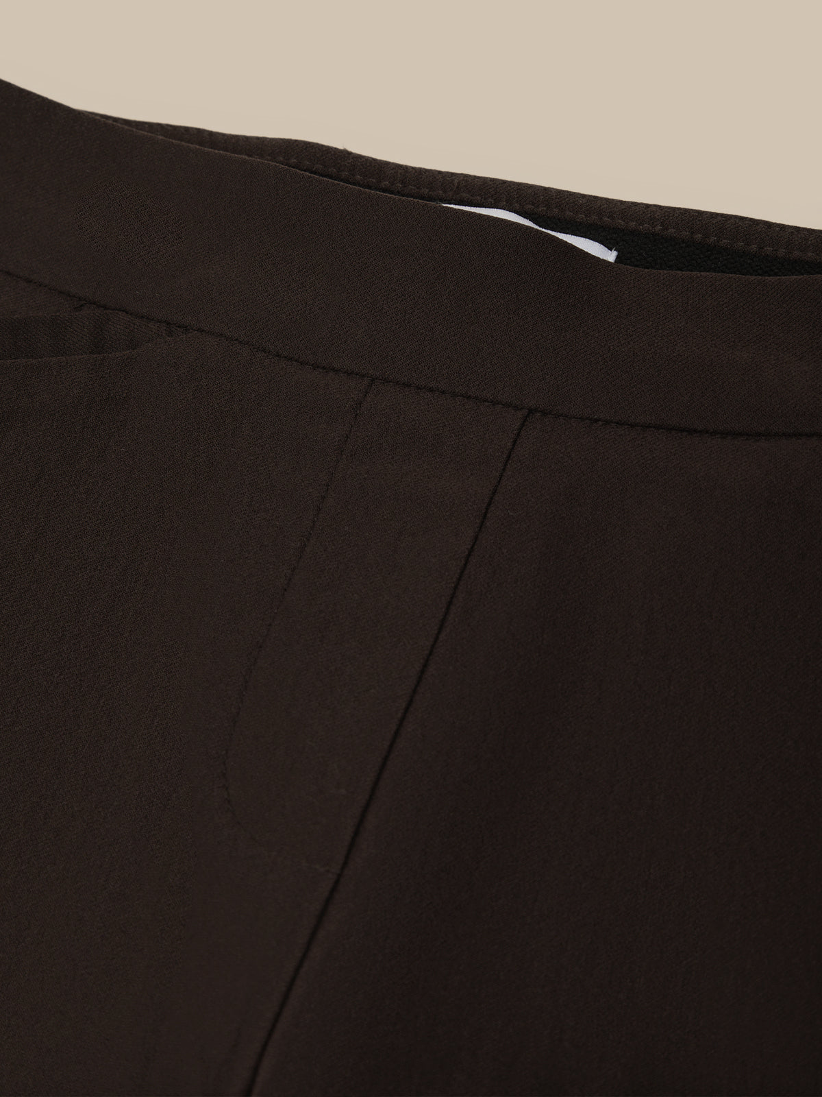 Close-up of a black fabric with a visible seam on a beige background