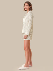 Woman wearing a white floral pajama set on a beige background