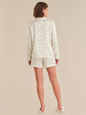 Woman wearing a light-colored floral pajama set on a beige background