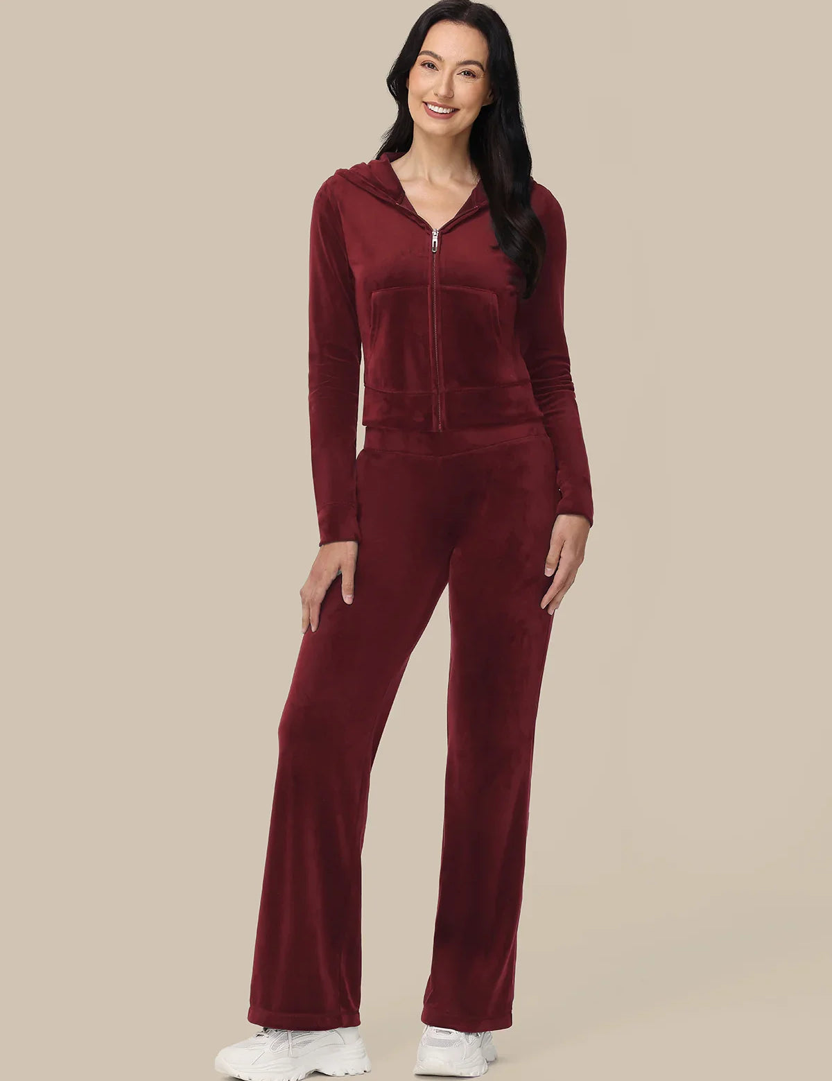 Woman wearing a burgundy tracksuit on a beige background