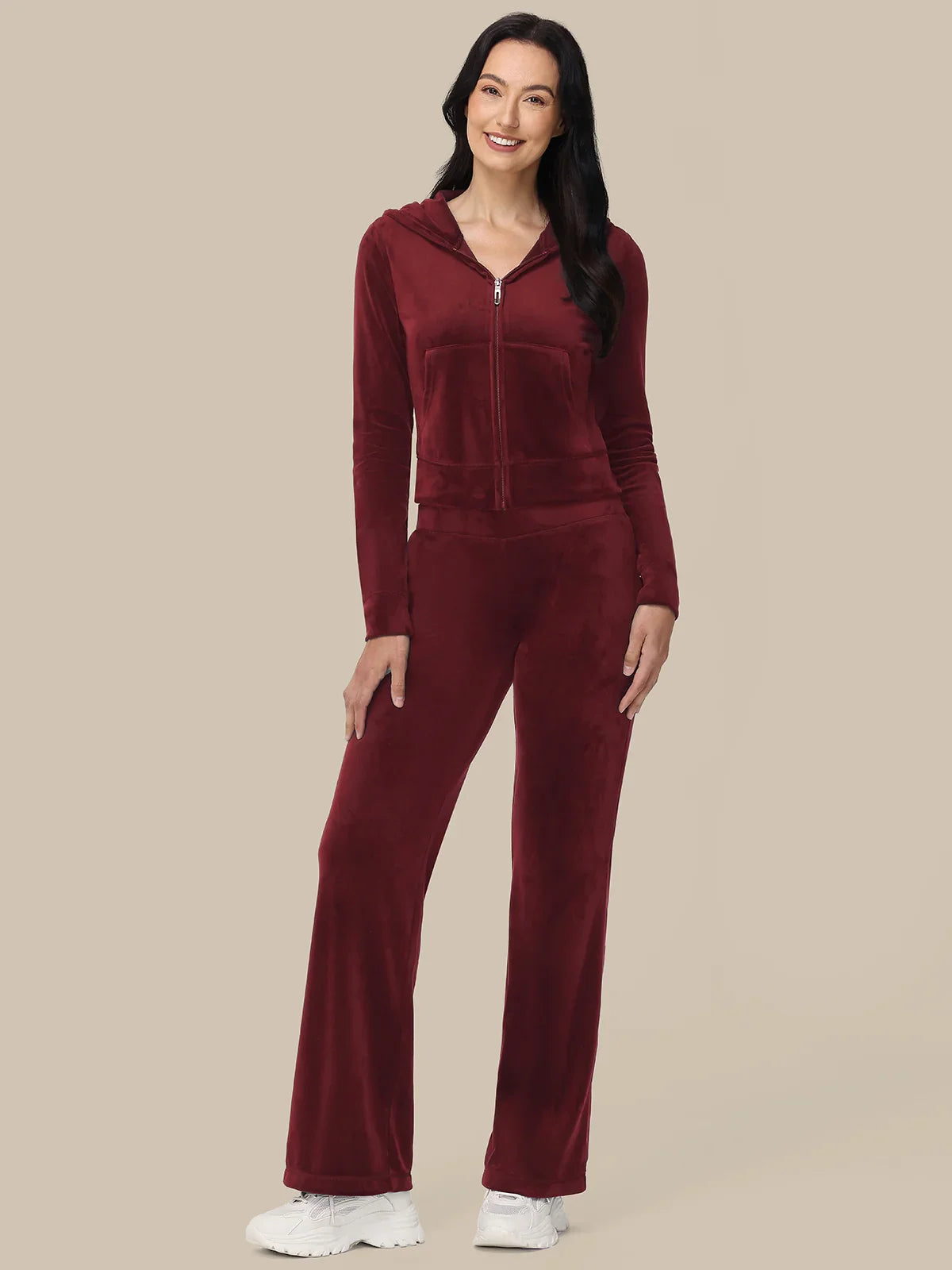 Woman wearing a burgundy tracksuit on a beige background