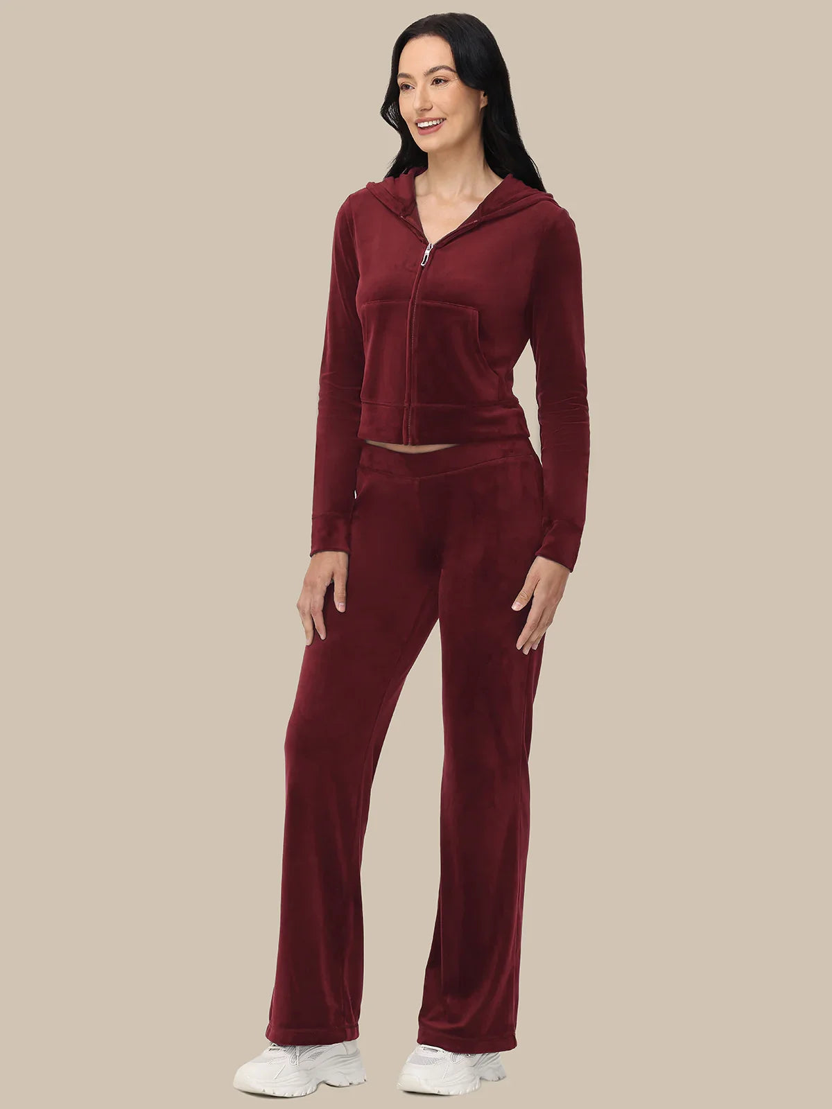 Woman wearing a burgundy tracksuit on a beige background
