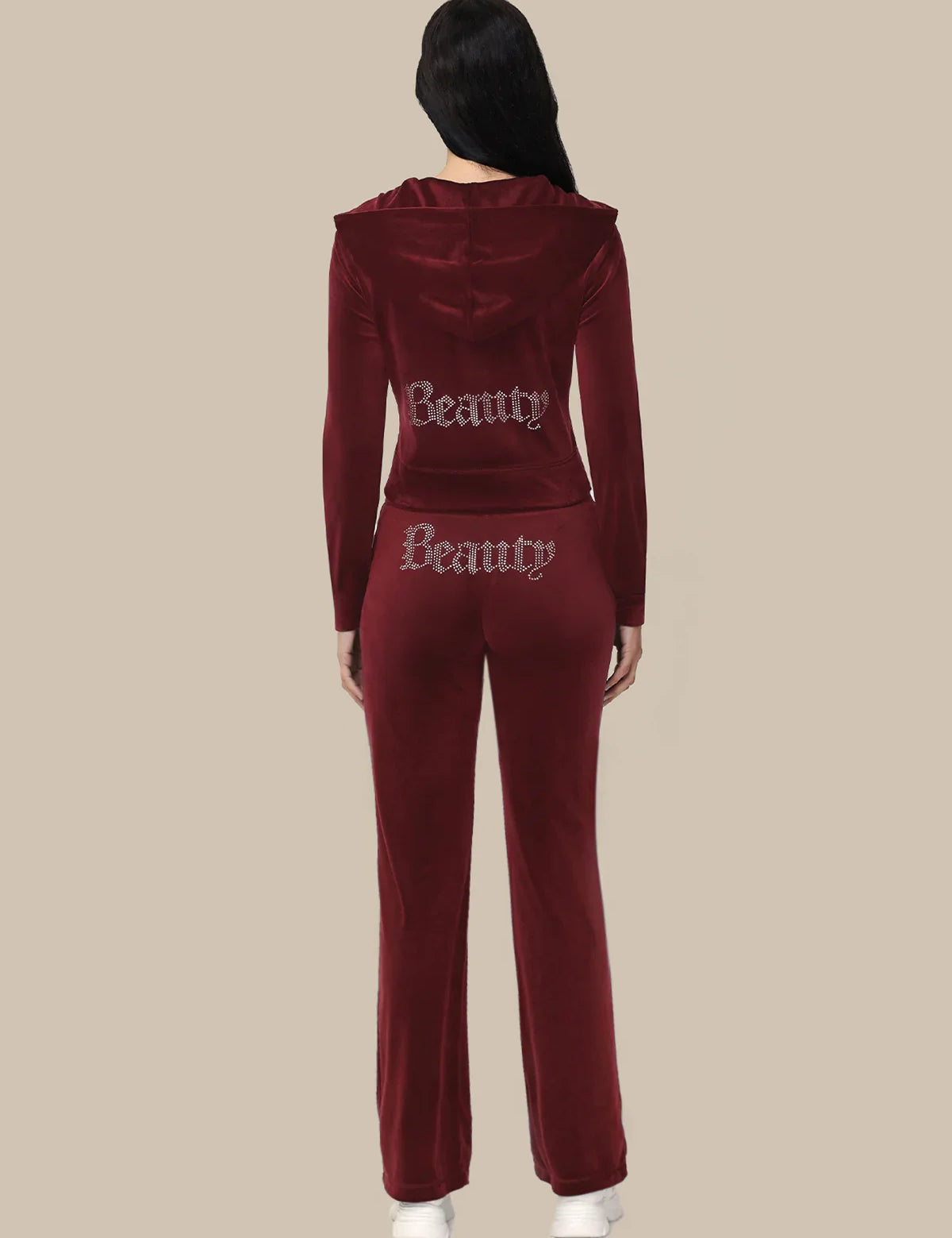Maroon tracksuit with 'Beauty' text on the back worn by a person against a beige background