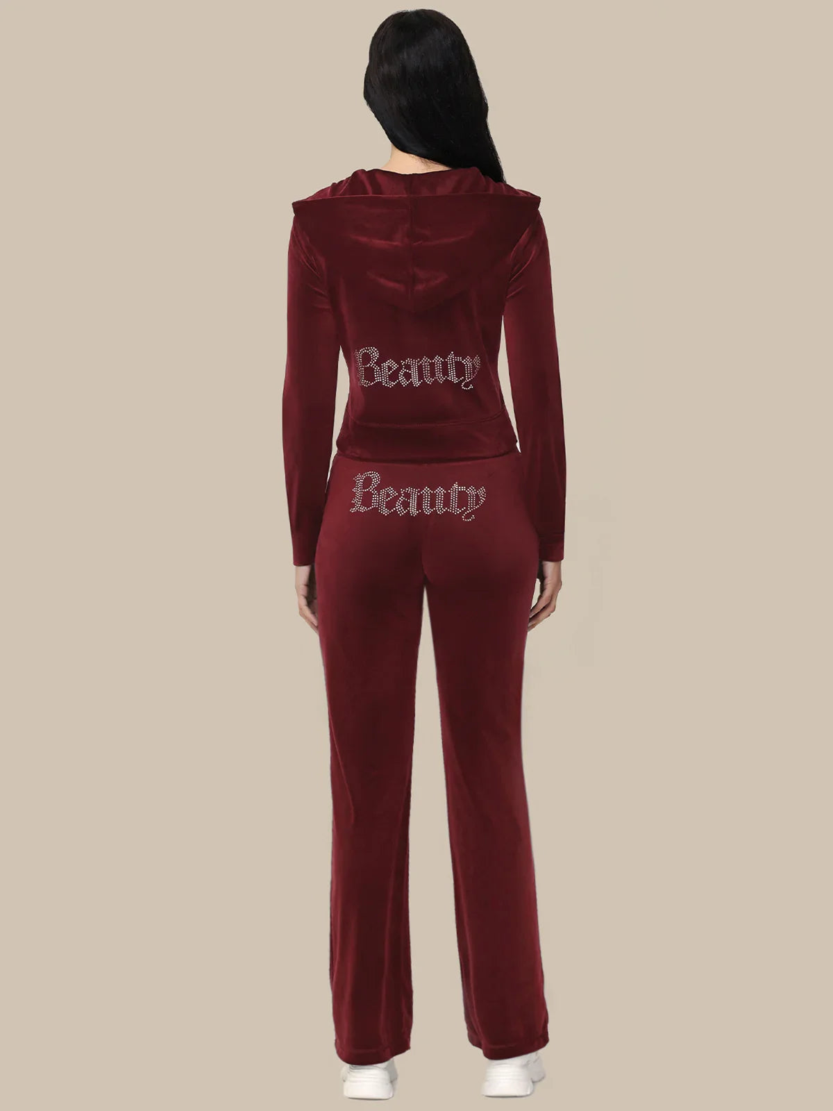 Maroon tracksuit with 'Beauty' text on the back worn by a person against a beige background