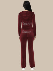 Maroon tracksuit with 'Beauty' text on the back worn by a person against a beige background