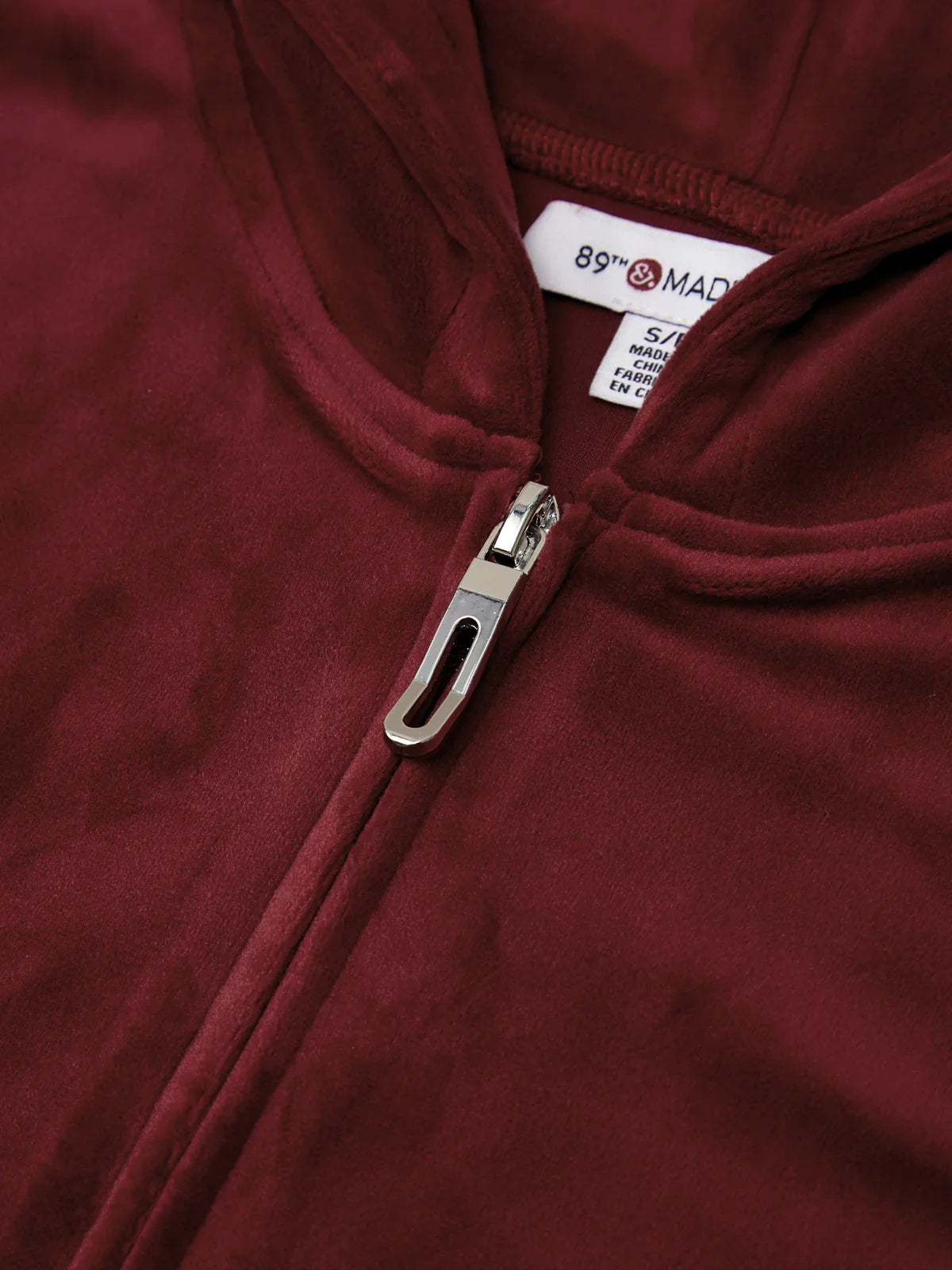 Close-up of a maroon jacket with a zipper and brand label.
